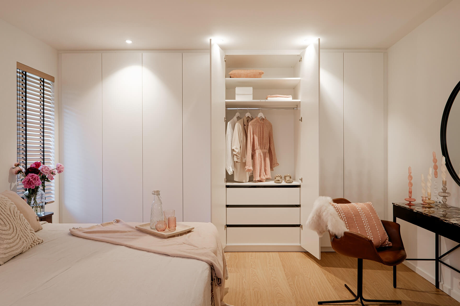 Ingebouwde witte dressing op maat in een sfeervolle slaapkamer met roze styling