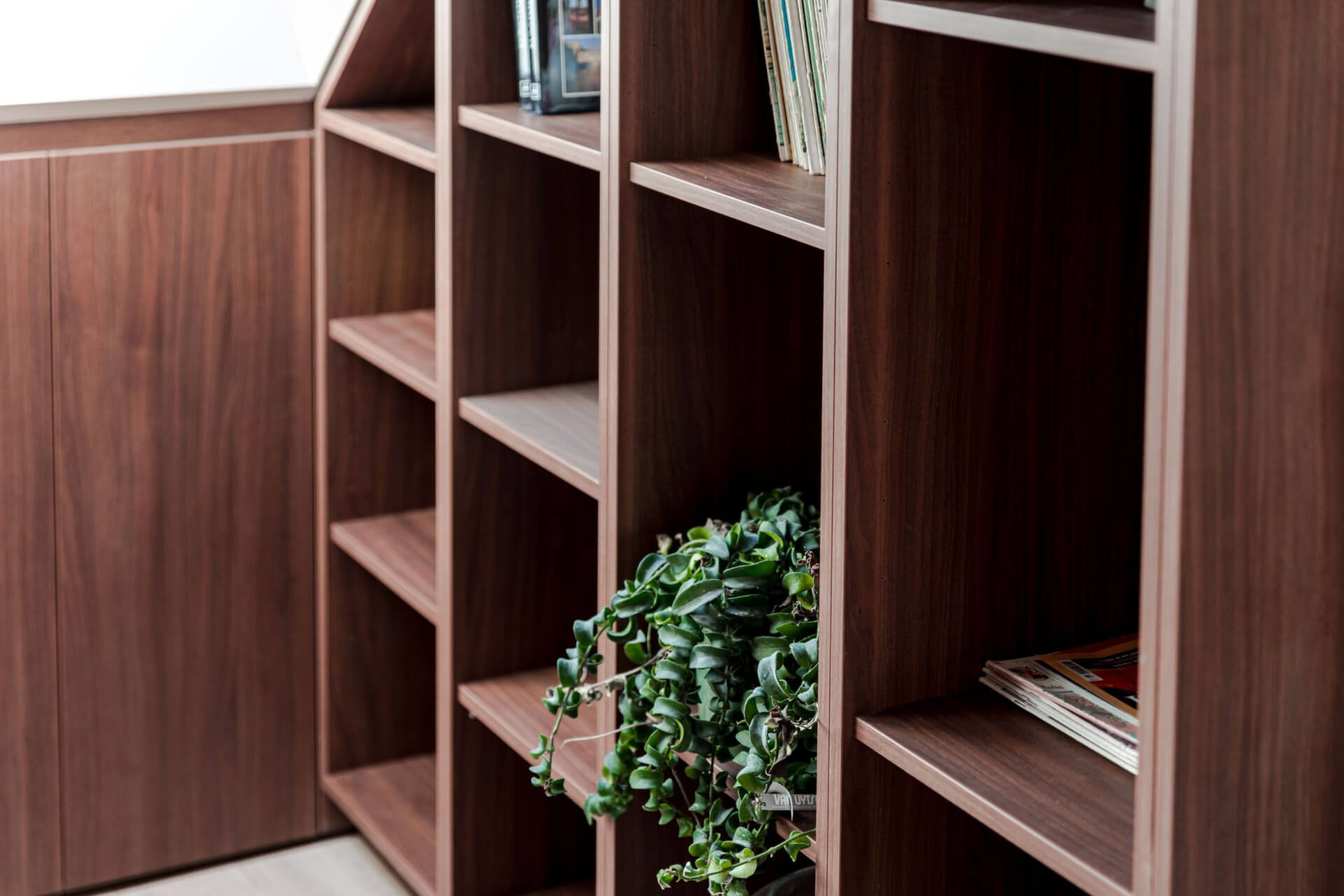Bibliothèque sur mesure en noyer qui suit le mur incliné d’un grenier