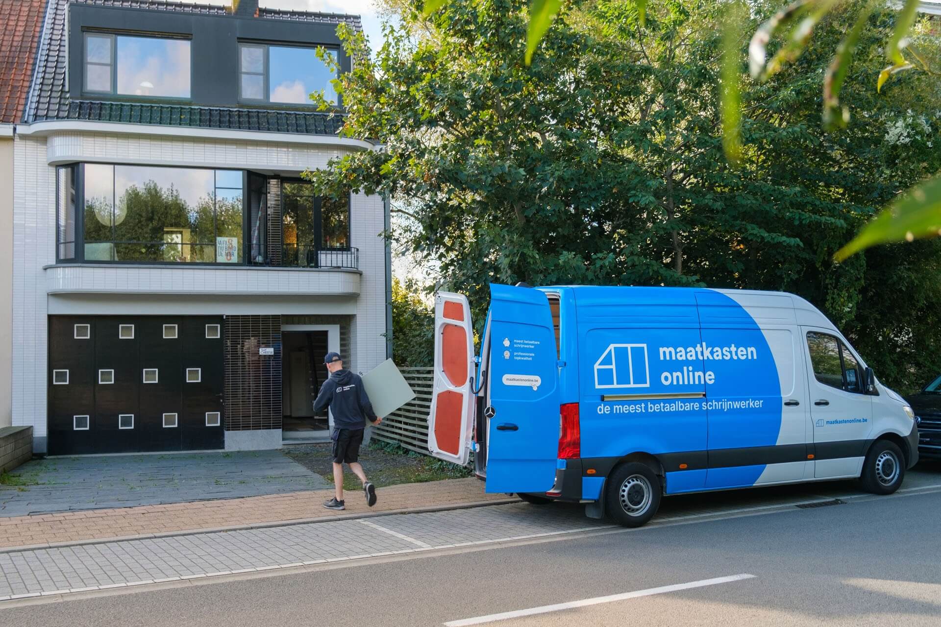 Een busje van Maatkasten Online staat voor een huis om de levering te voltooien