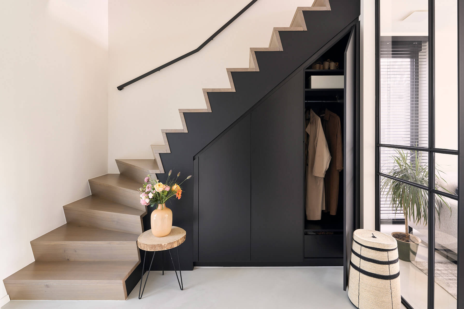 Armoire sur mesure noire sous un escalier dans un hall d'entrée