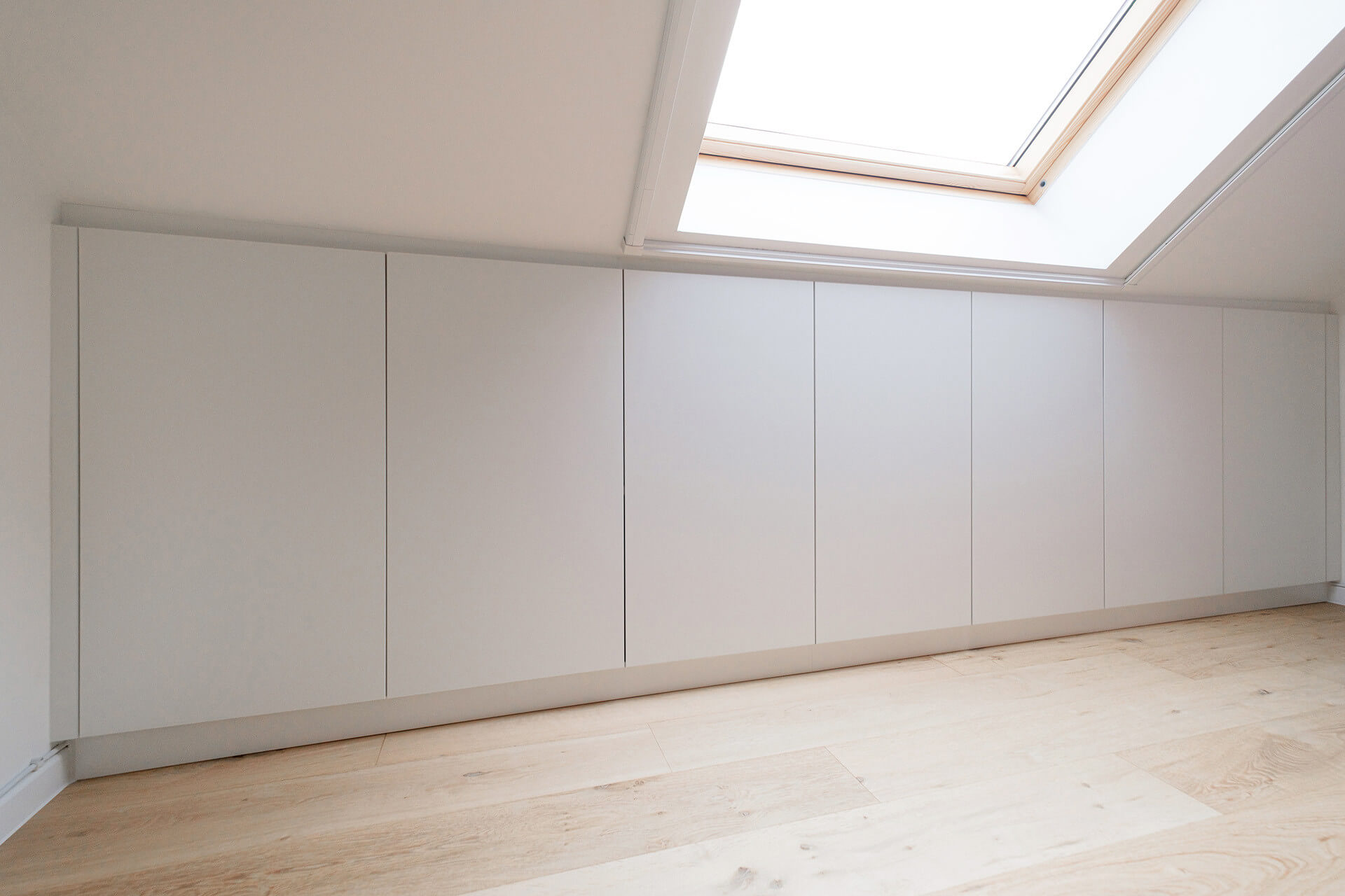 Custom storage cabinets under a sloping roof.