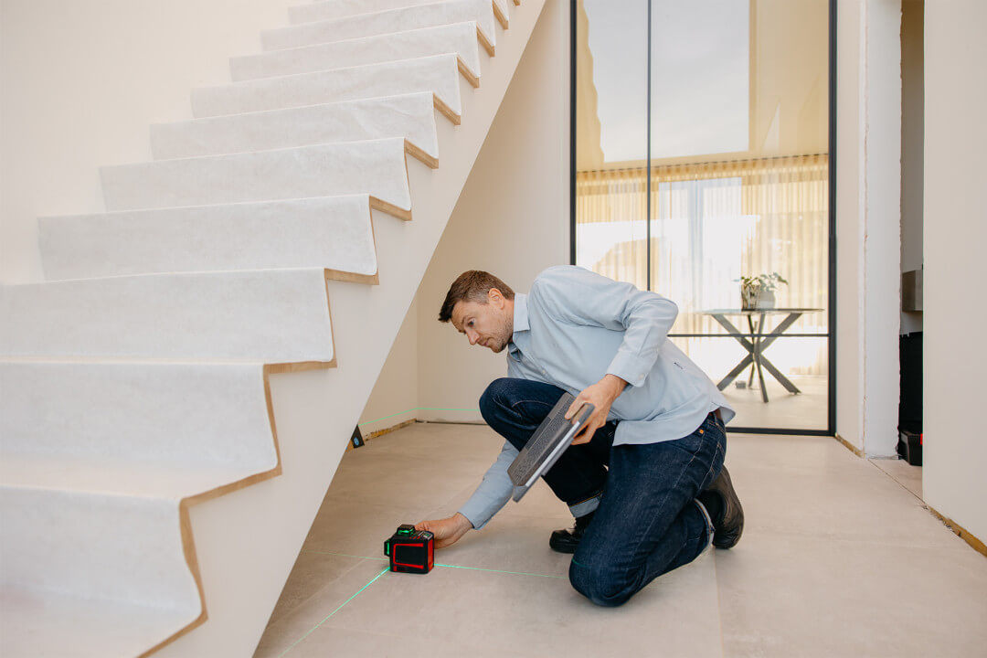 Professional measuring the space beneath stairs