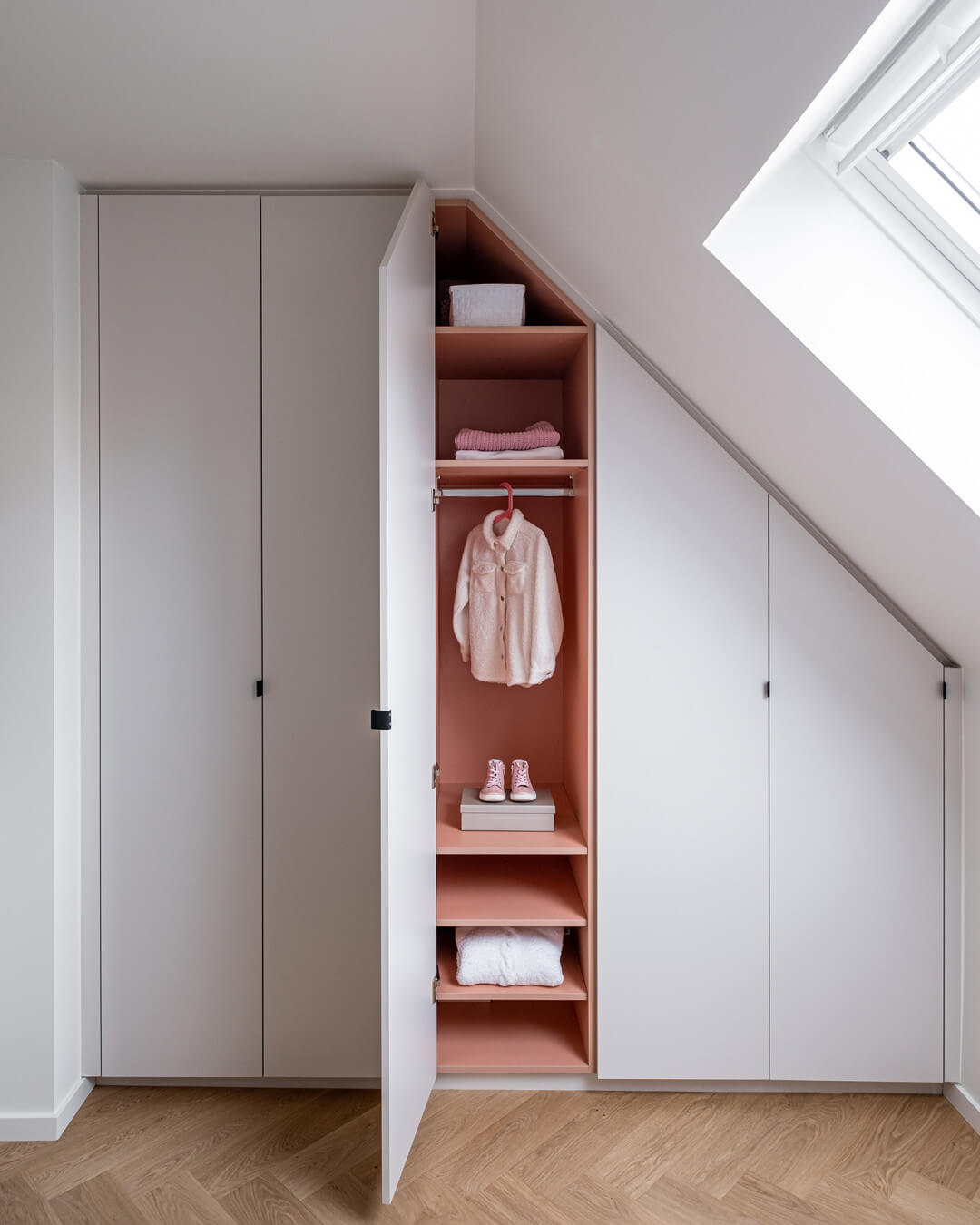 Custom-made wardrobe designed for an angled ceiling, featuring Dusty Coral as the interior color
