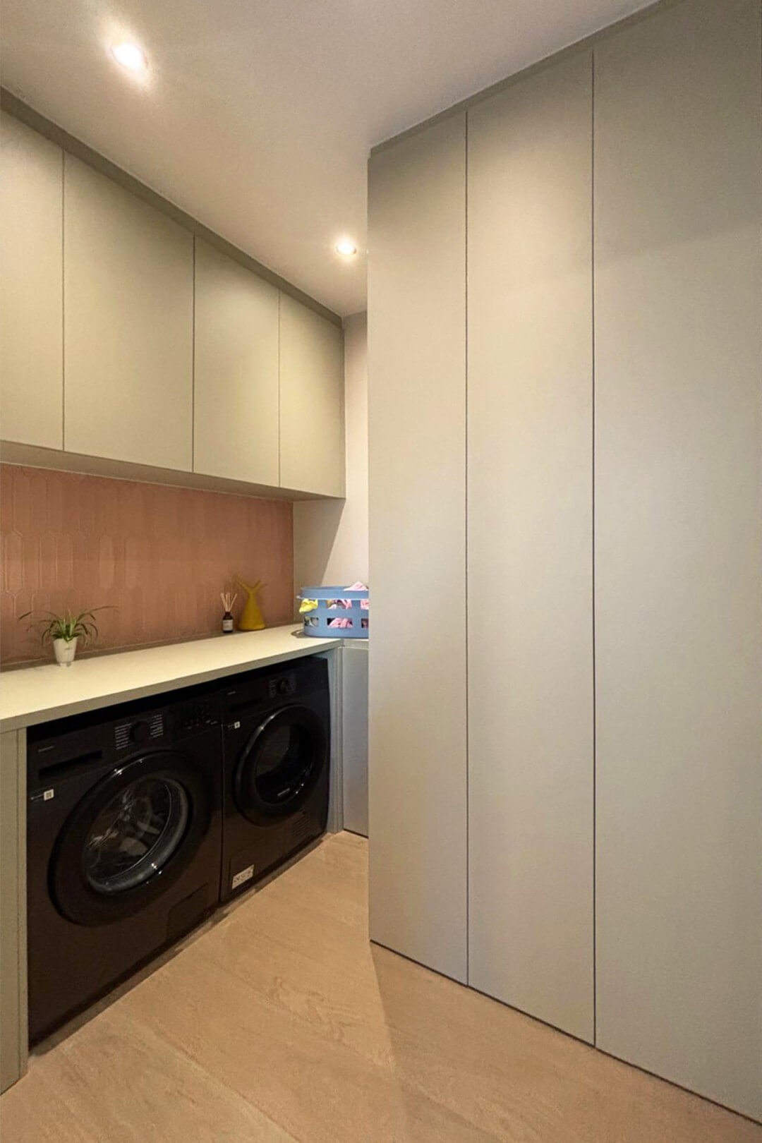 La combinaison d'une buanderie basse bas sur mesure et d'un meuble technique, tous deux de Maatkasten Online.