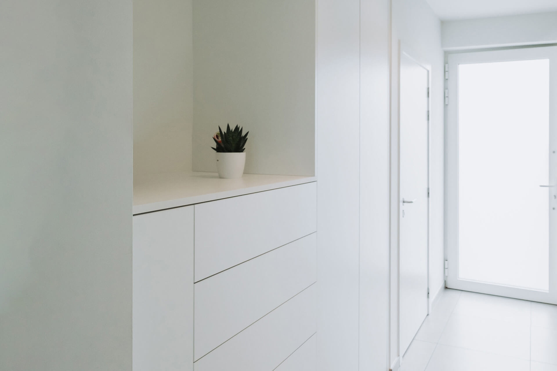 Customised white built-in storage cabinets in the entrance hall 