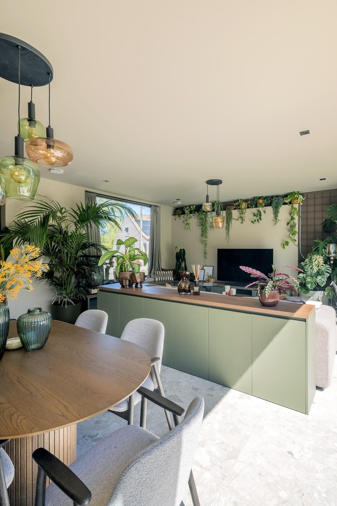 Deelnemers Langdorp VTM programma Huis Gemaakt shot vanuit woonkamer met zicht op de tv meubel met doorlopende zitbank in Green Shadow en Lorenzo Walnut bovenblad en commodekast middenin de ruimte