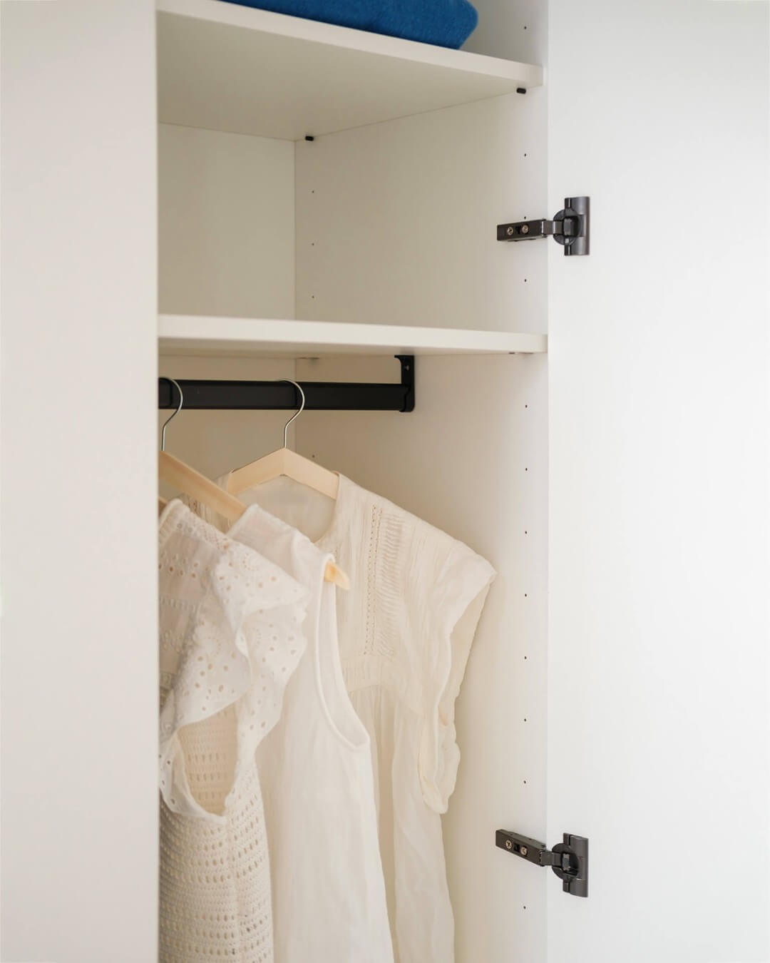 Details of made-to-measure wardrobe with black hinges and black clothes rod