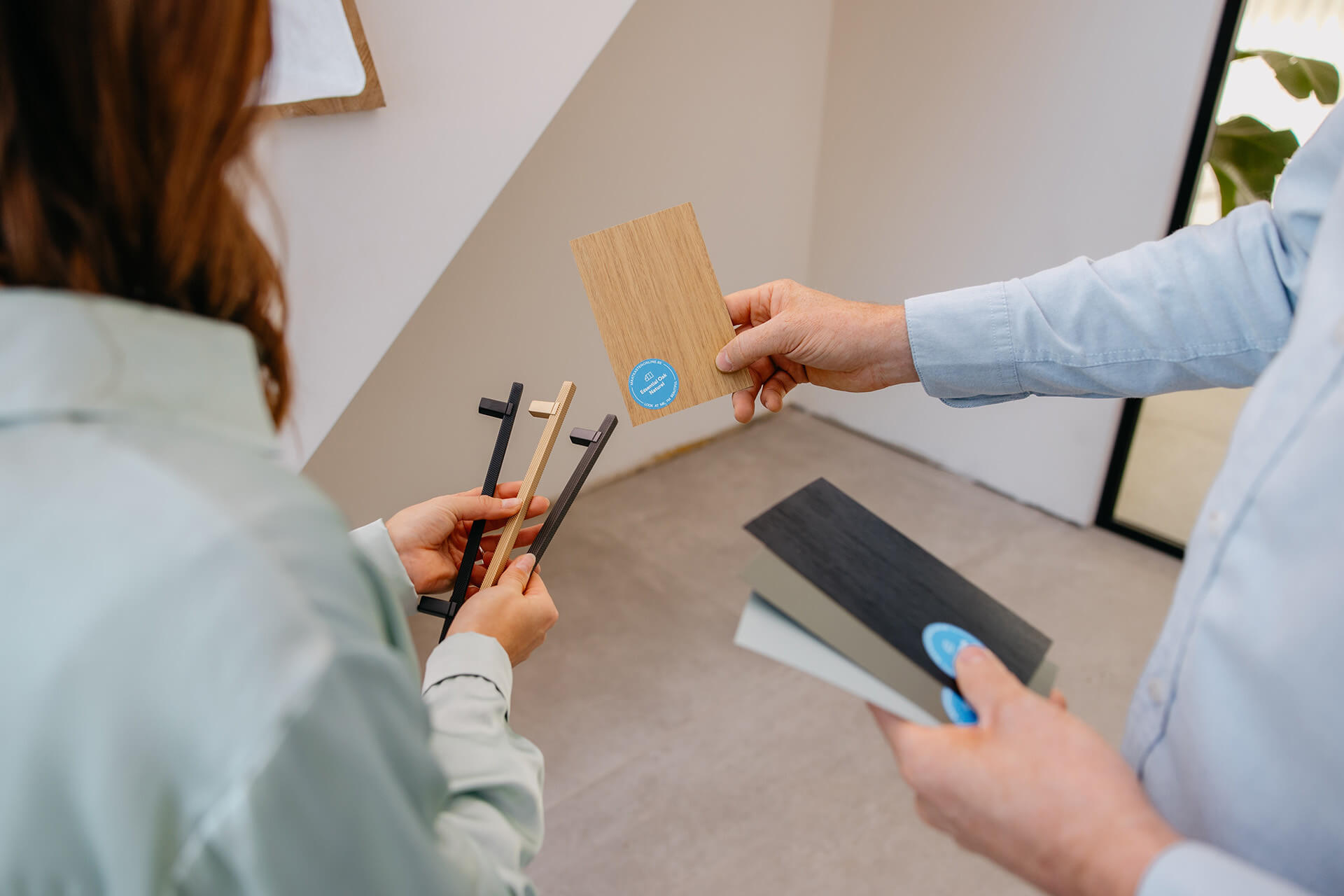 A man and a woman look at handles and colour swatches for bespoke wardrobes