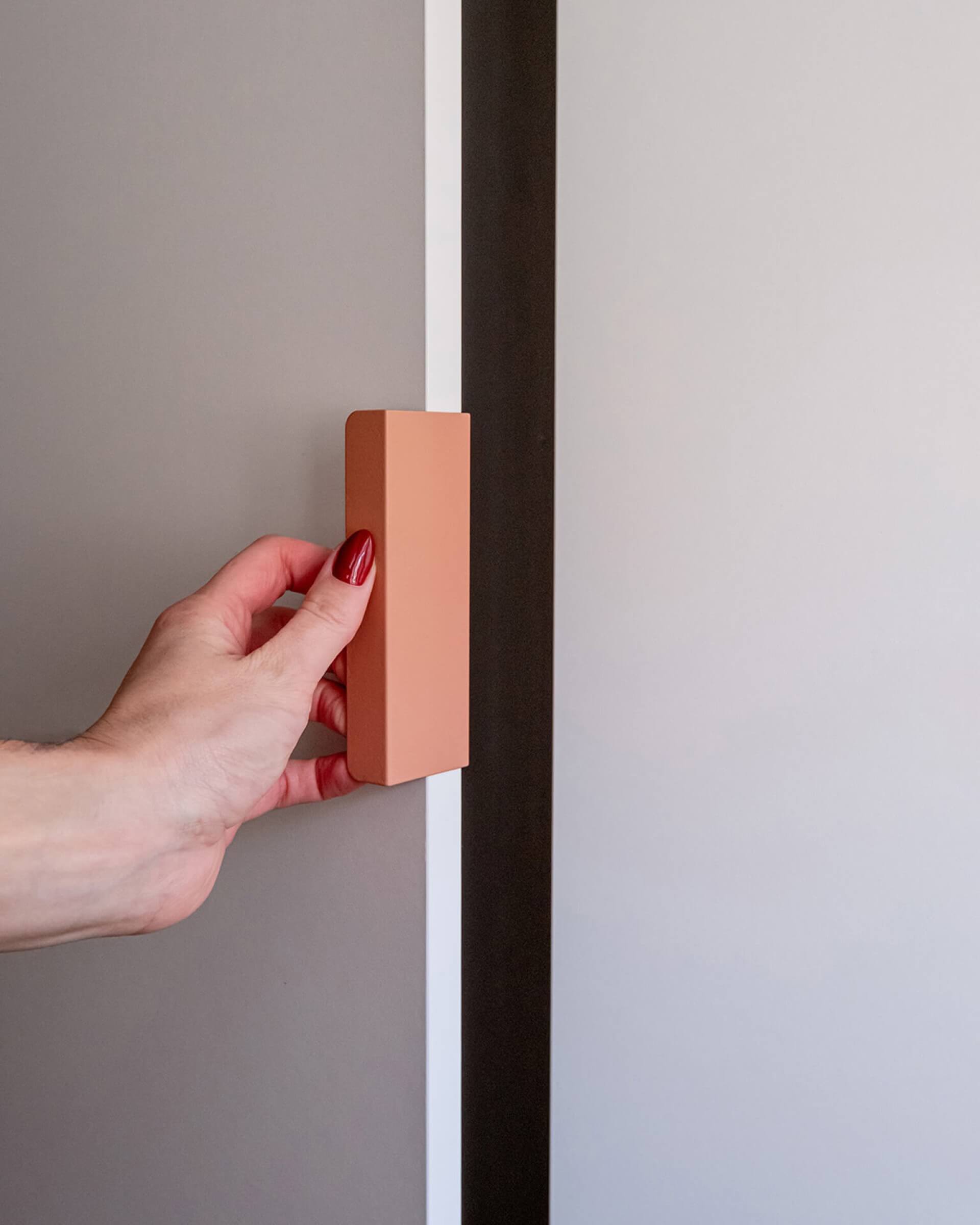 Pink Tonton handle on a white cupboard door