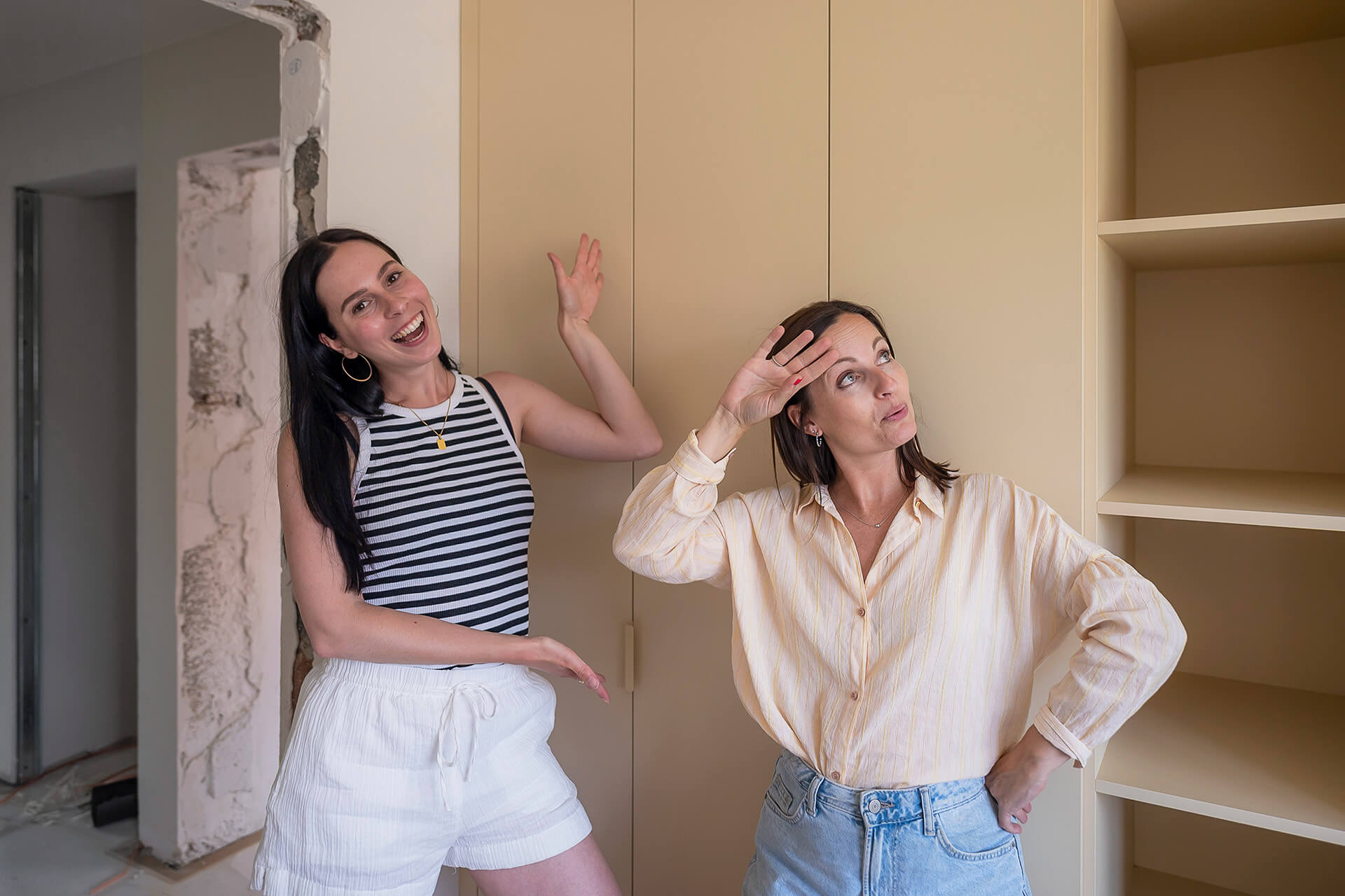 Eline and Zara proudly stand in front of the bespoke wardrobe they installed themselves