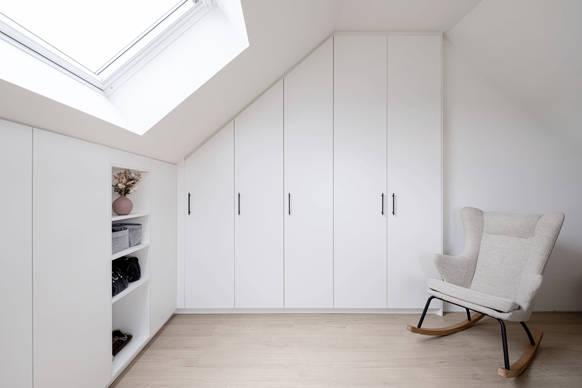 Custom built-in white storage cabinet designed for under a sloping roof.