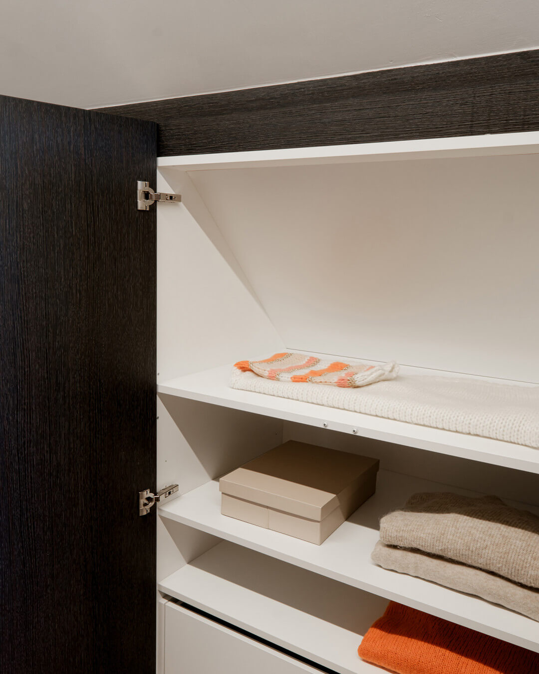 Walk-in dressing room under a sloping roof in the Hudson Oak color, from Maatkasten Online.