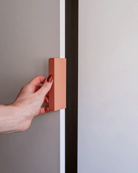 Detail shot van een roze Tonton handgreep die werd gemonteerd op een witte maatkast. Links in de foto zien we een hand de kast open doen.