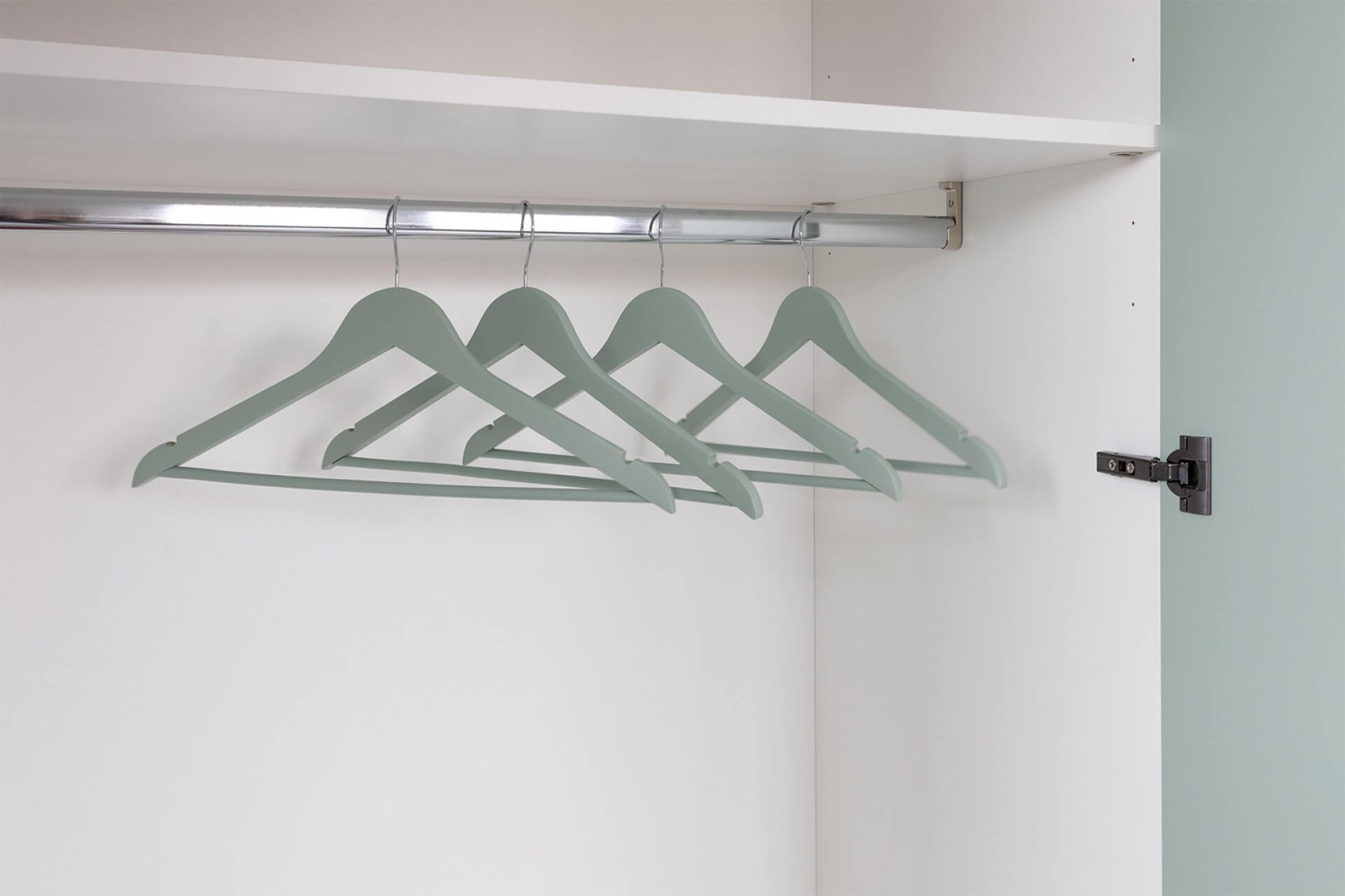 Sfeerbeeld van kledinghangers Industrial Green die in witte kledingkast hangen, zonder kledij.