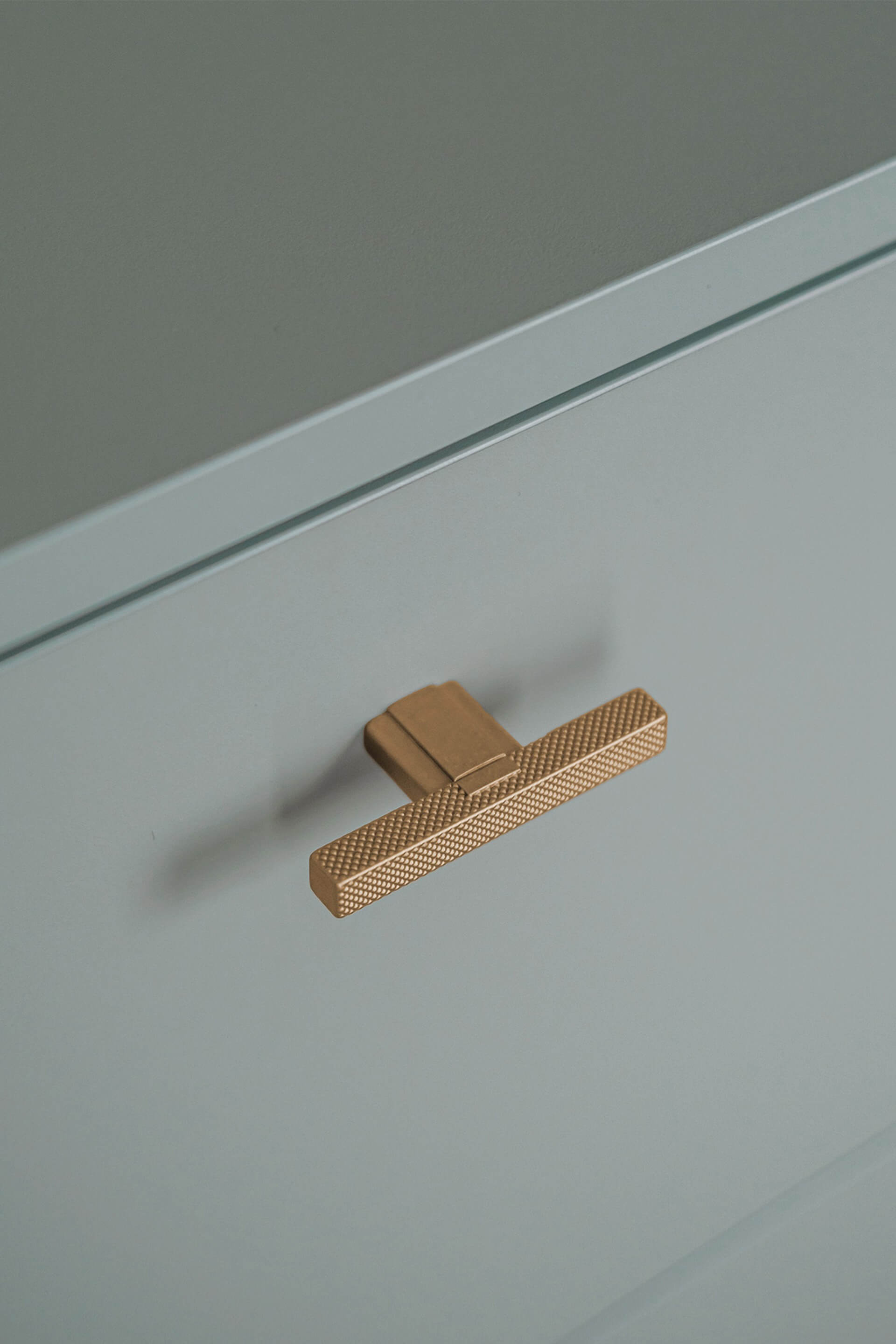 Detail shot of the T-Diamond handles in brass on a custom-made storage cabinet in Industrial Green.