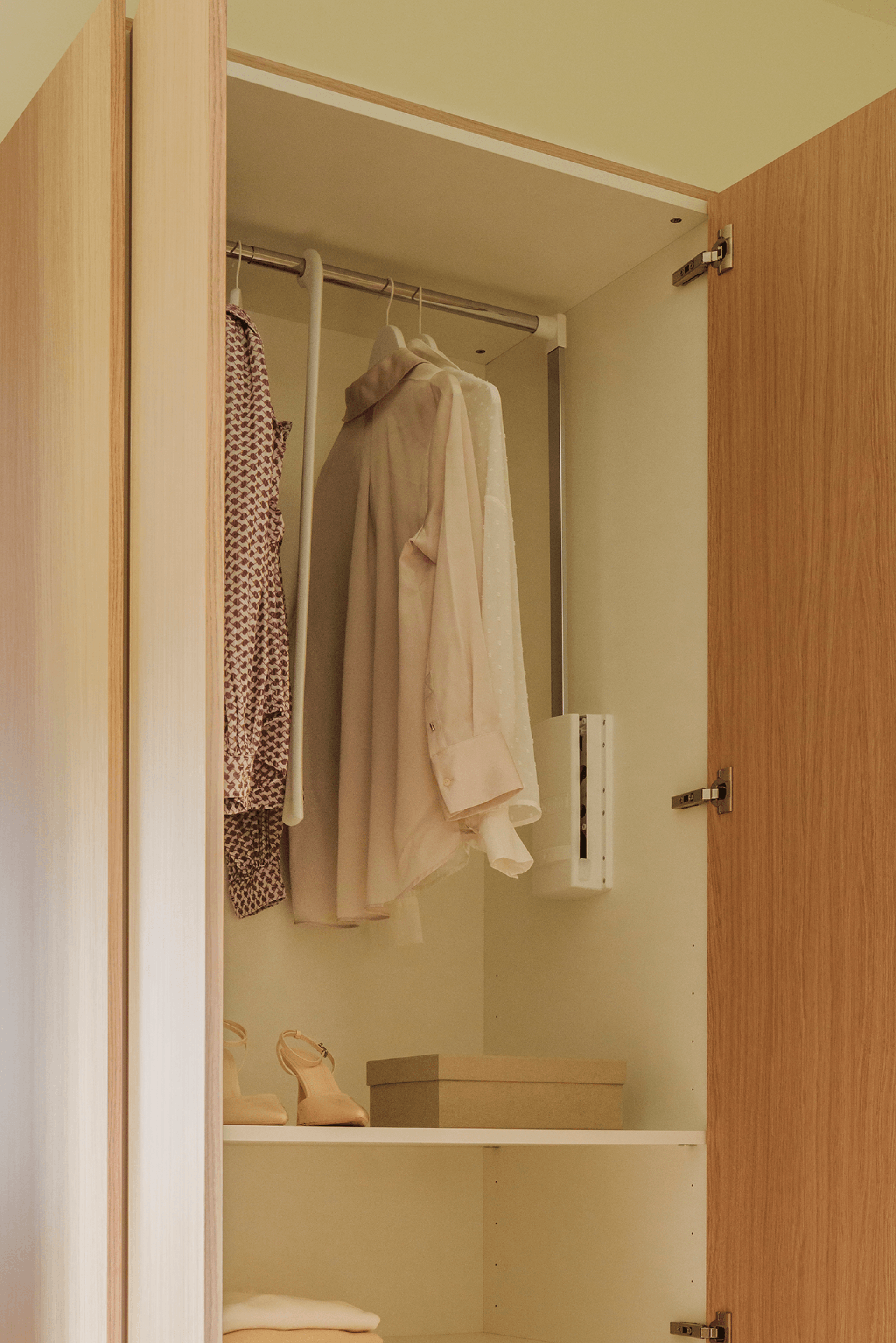 Sfeerbeeld van een witte kledijlift met kleren voor in je kasten op maat. Beschikbaar in de boetiek van Maatkasten Online.