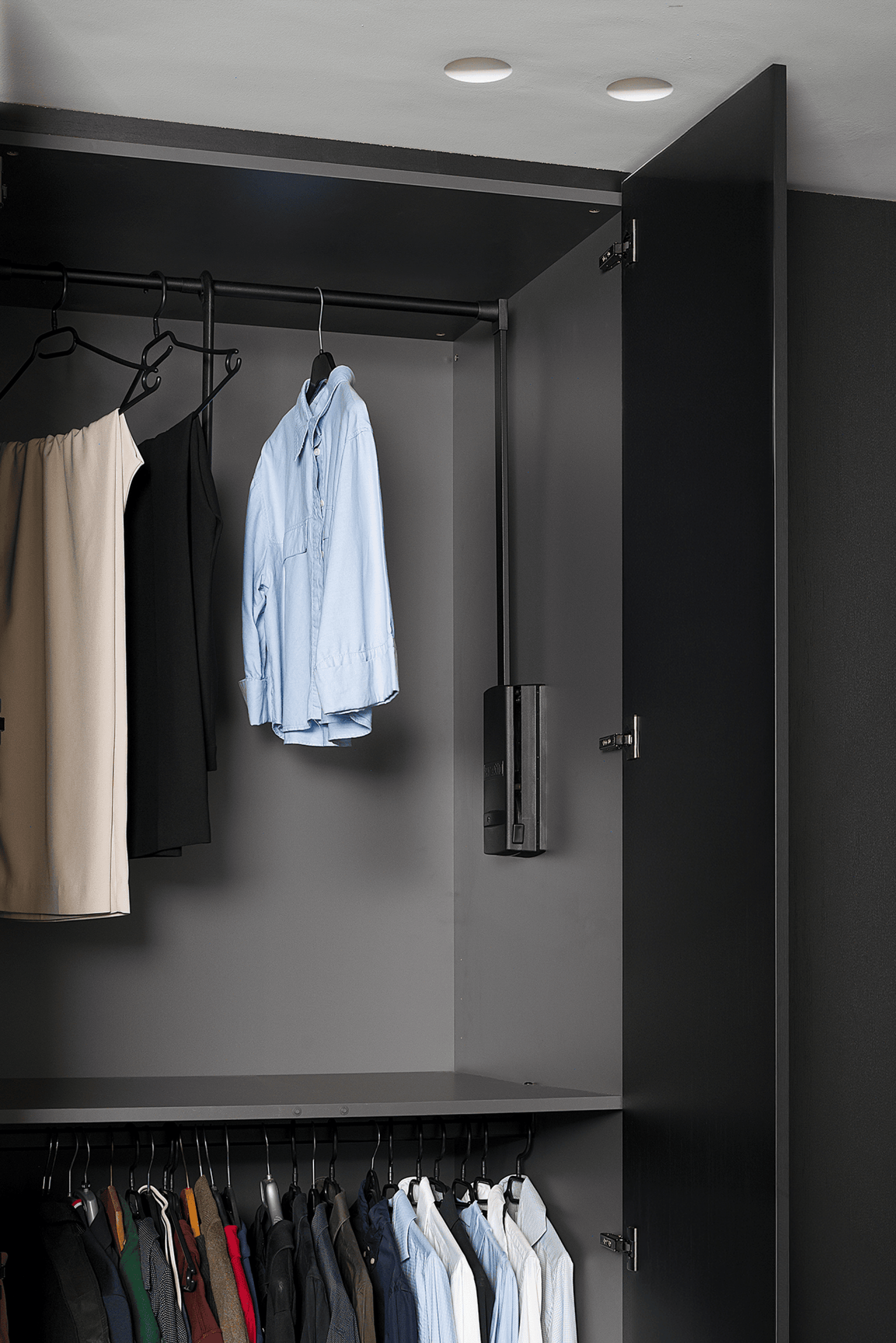 Atmospheric image of a black garment lift with clothes from the Maatkasten Online boutique.