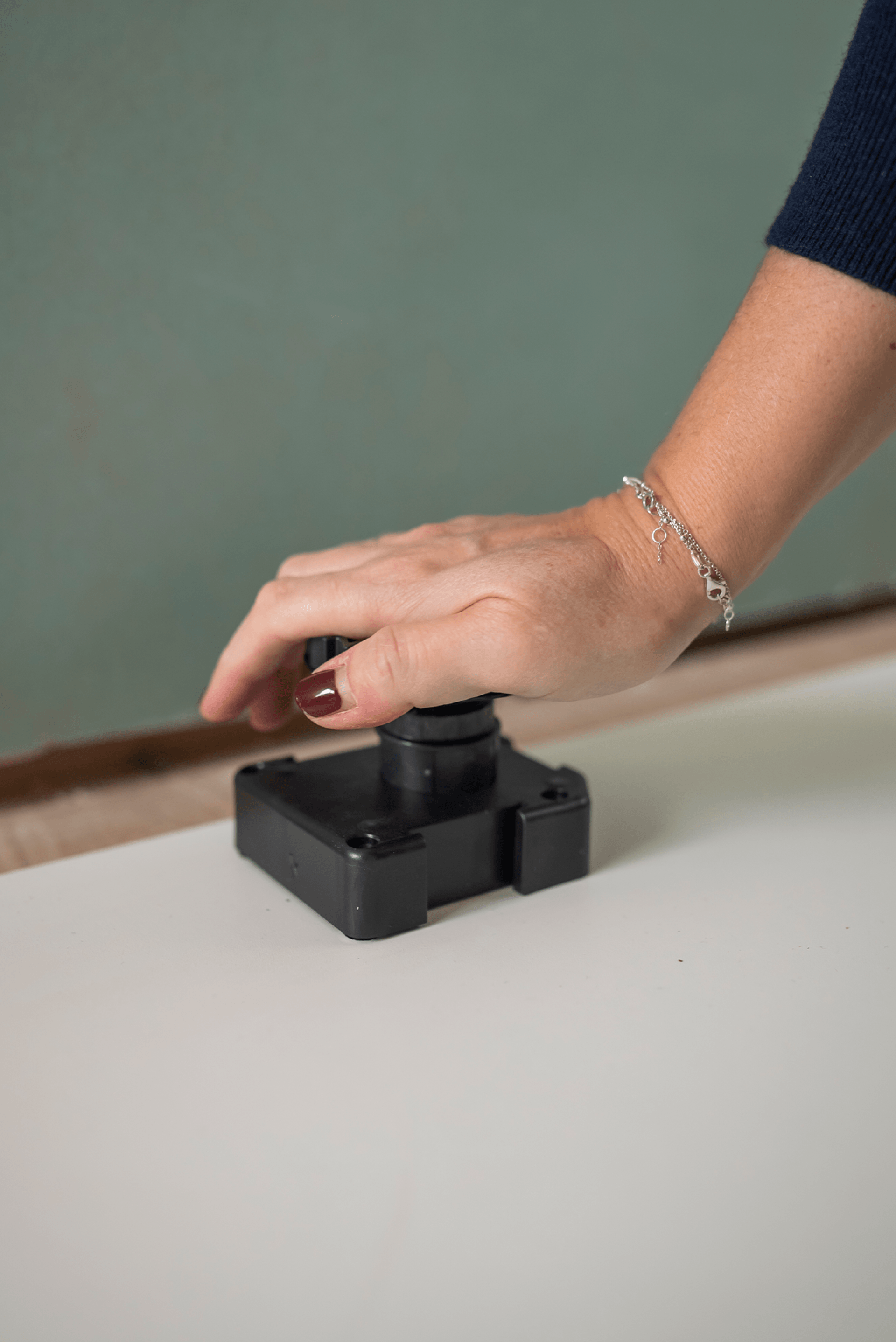 Pied de socle de 60 mm emboîté sur la base du socle. Ces pieds robustes en plastique servent de base aux meubles sur mesure, assurent une stabilité optimale et sont facilement réglables. Le gros plan montre la partie supérieure et le système d'engrenage permettant un réglage précis.